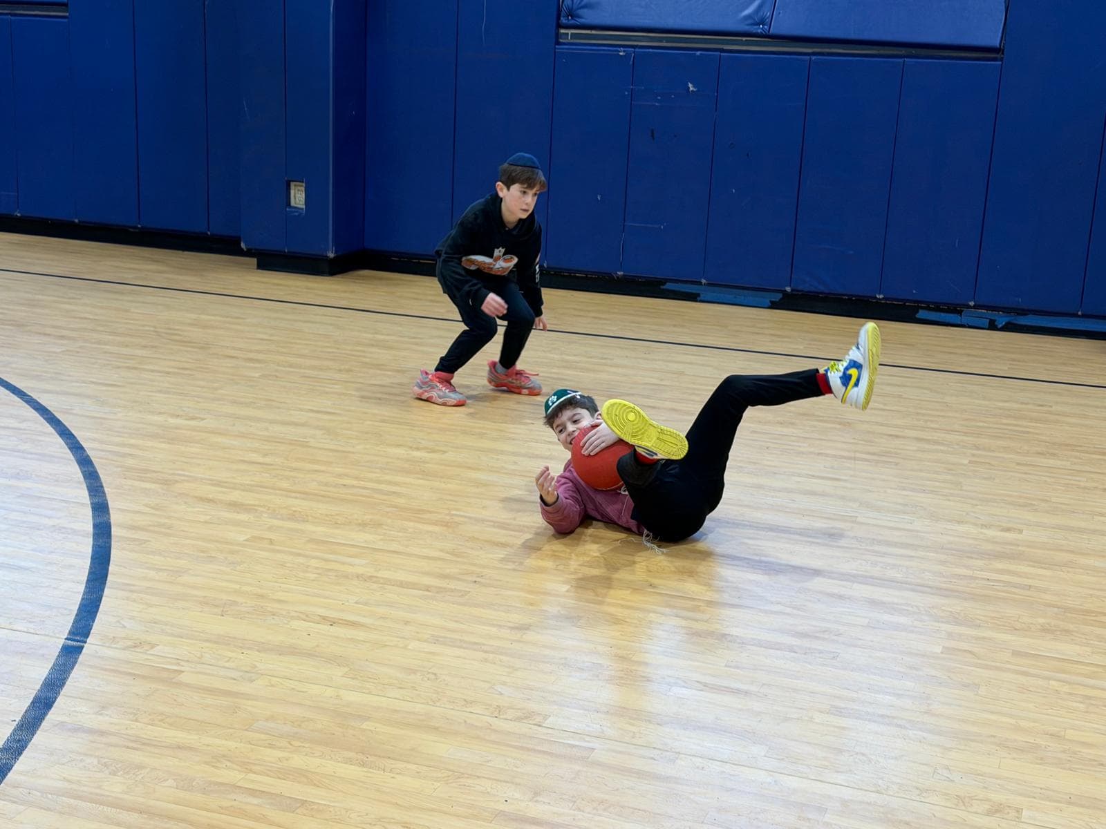 A boy diving to the gym floor with a dodgeball