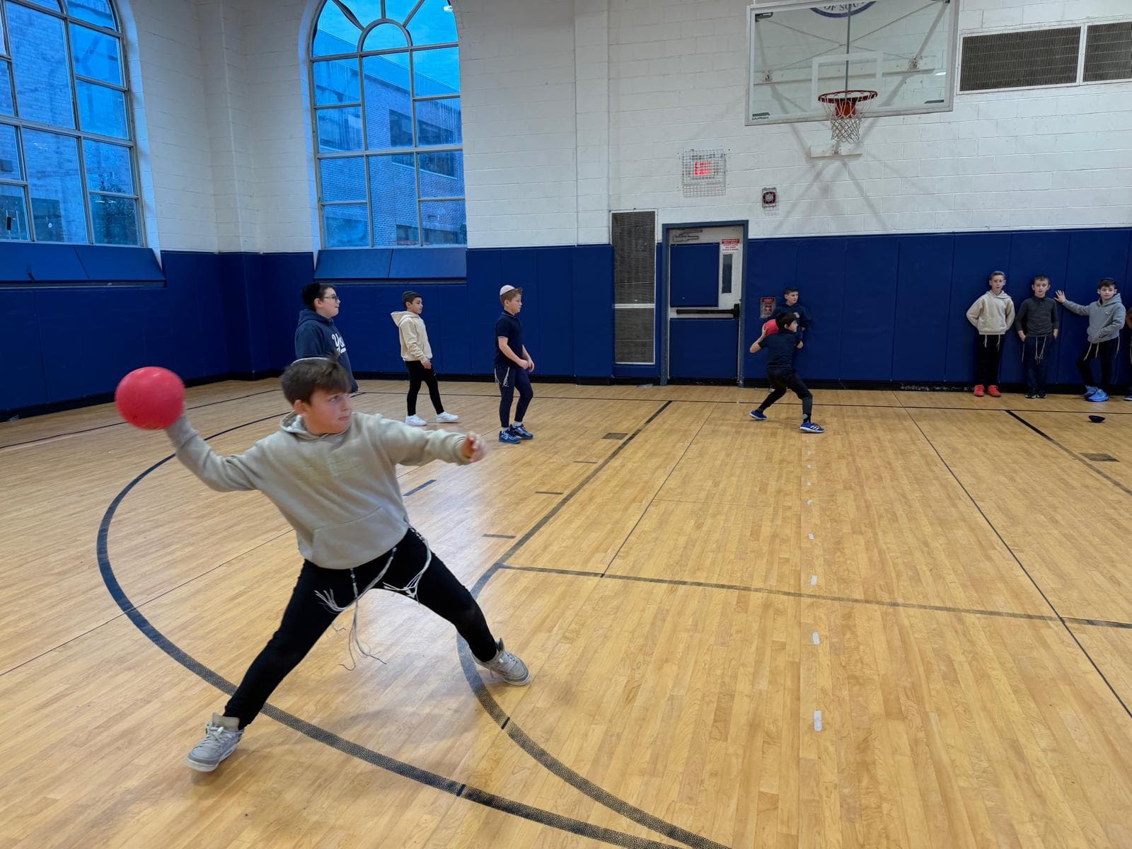 A boy winding up to throw in a gym dodgeball game