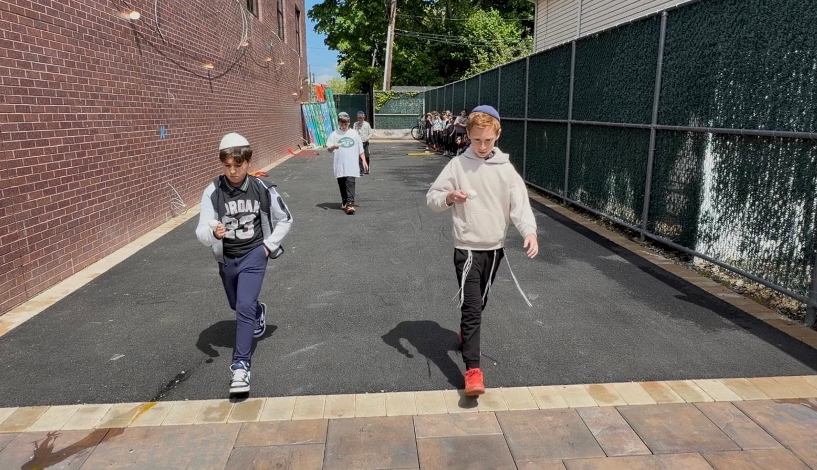 Two boys racing across the yard balancing a ball on a spoon